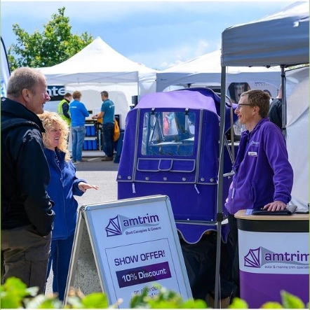 image of an Amtrim representative at a boating show happily speaking to a couple