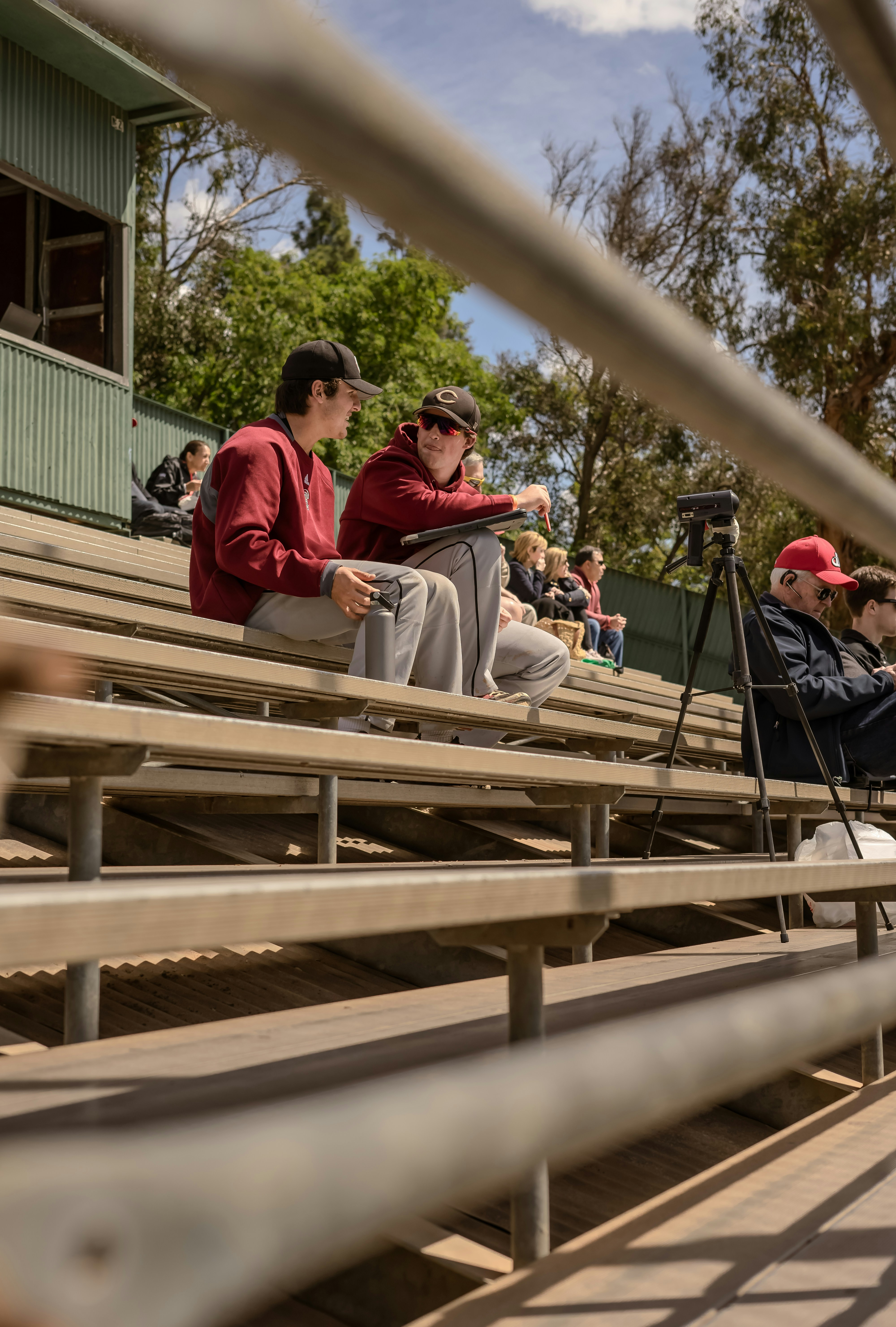Two people seated on bleachers watching a game