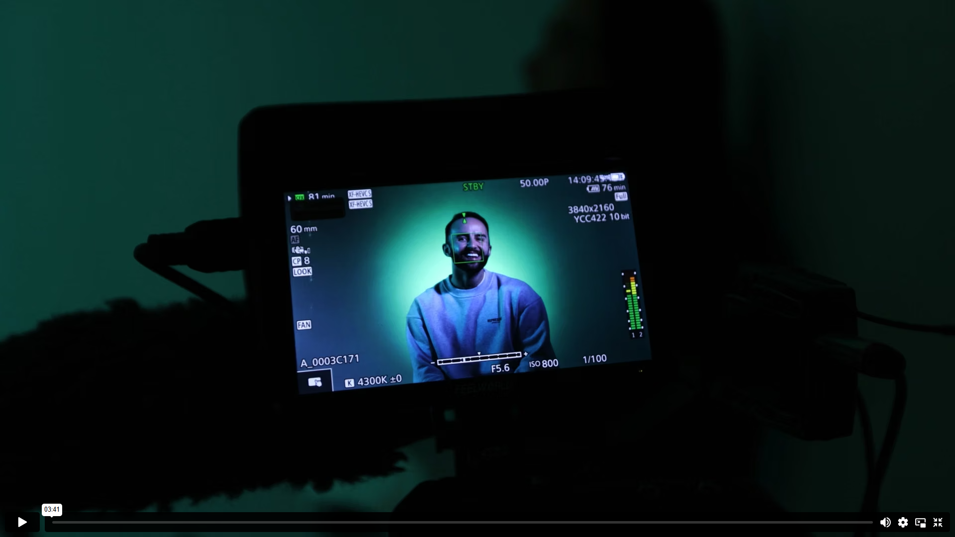 Video still — Ben Lane seated on set, green studio lighting