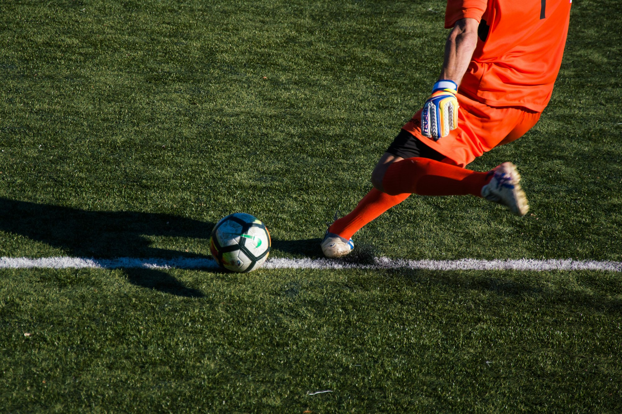Footballer on grass in orange kit, aerial