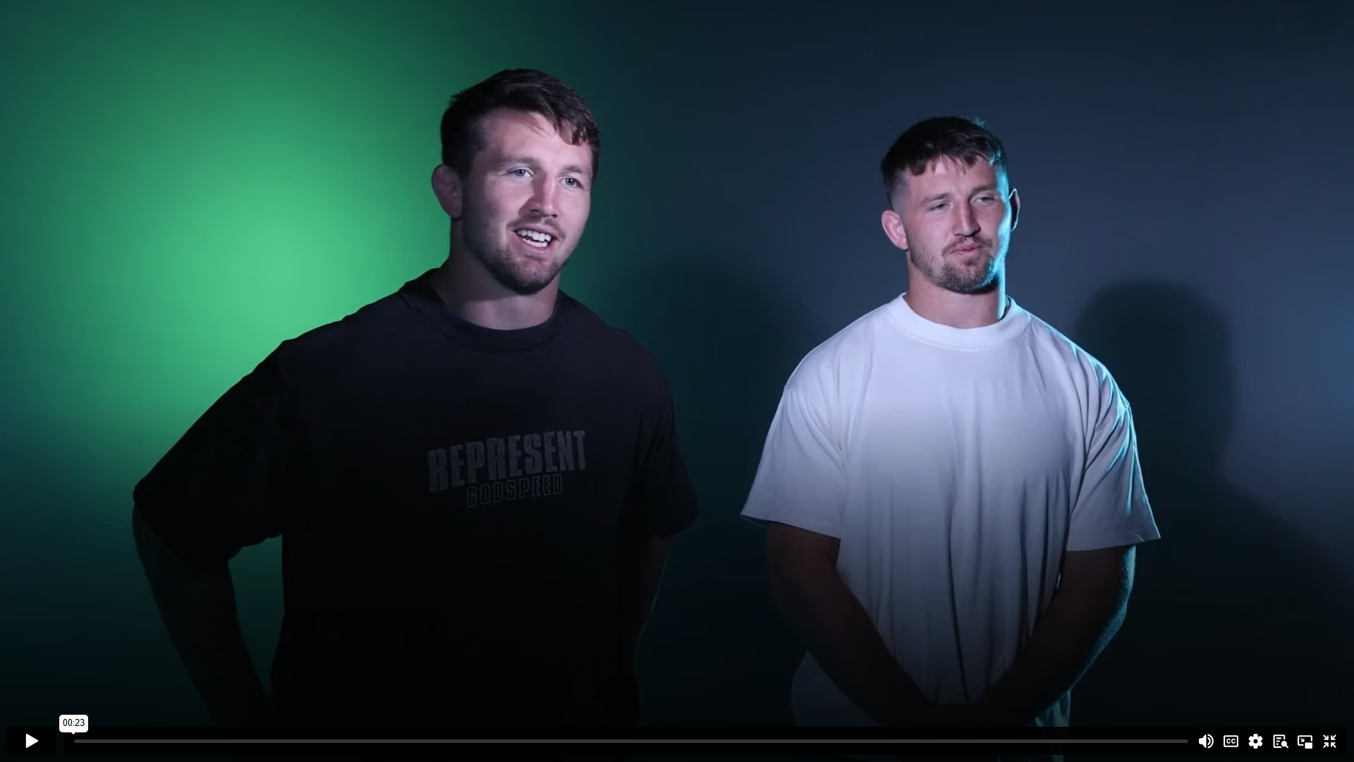 Video still — Tom and Ben Curry seated on set, green studio lighting