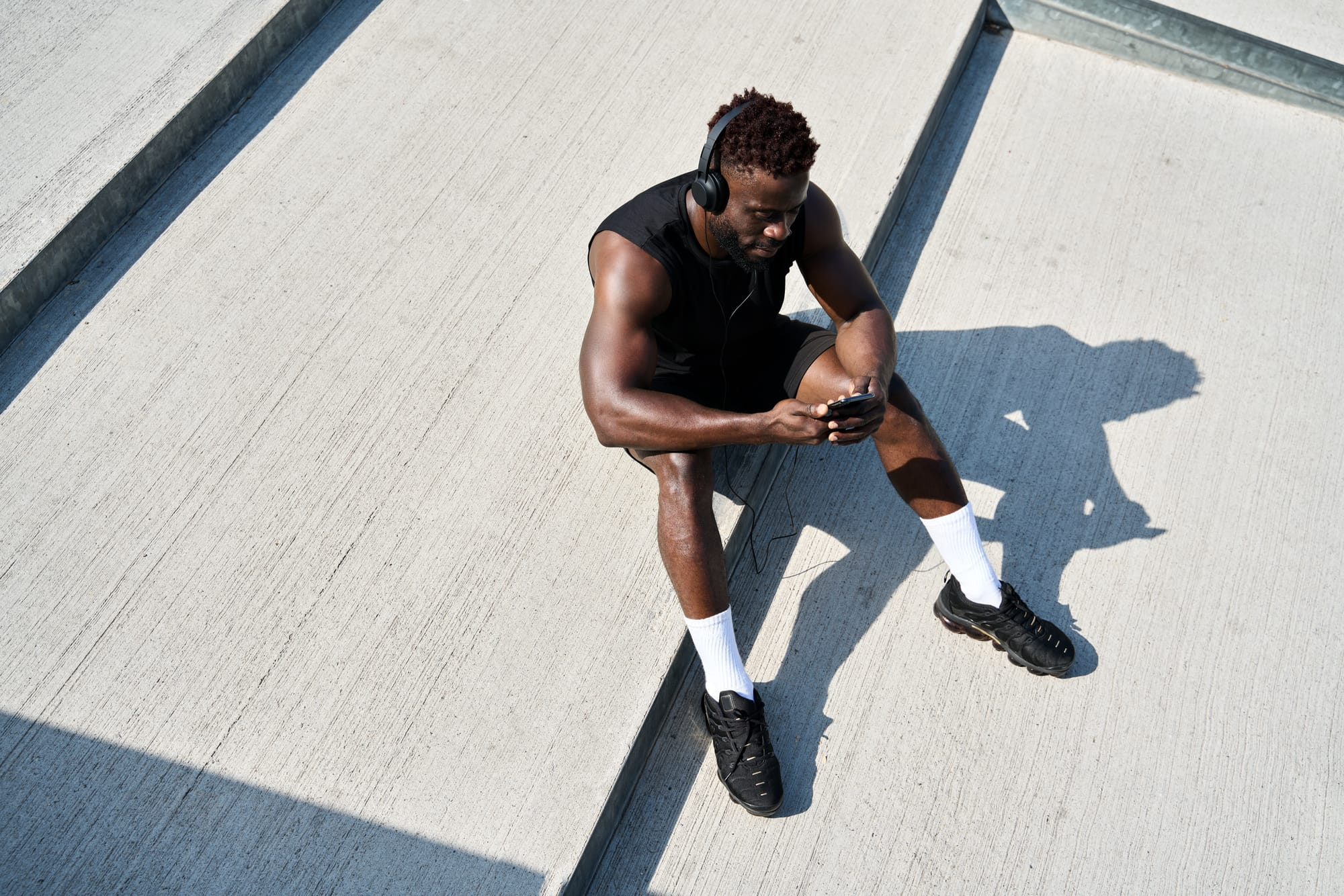 Athlete seated on outdoor steps checking phone