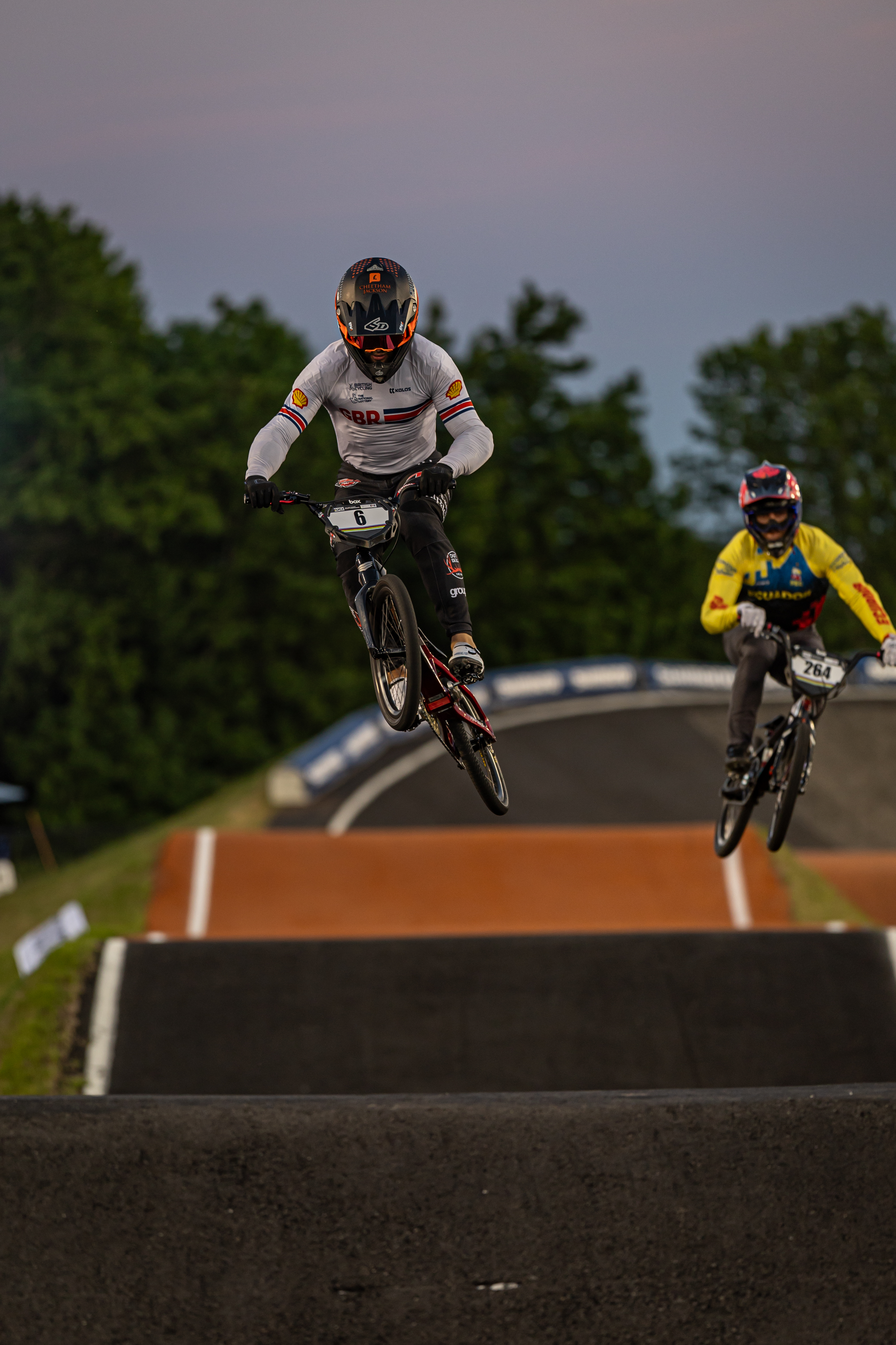 Hero — BMX racer mid-jump, trees behind
