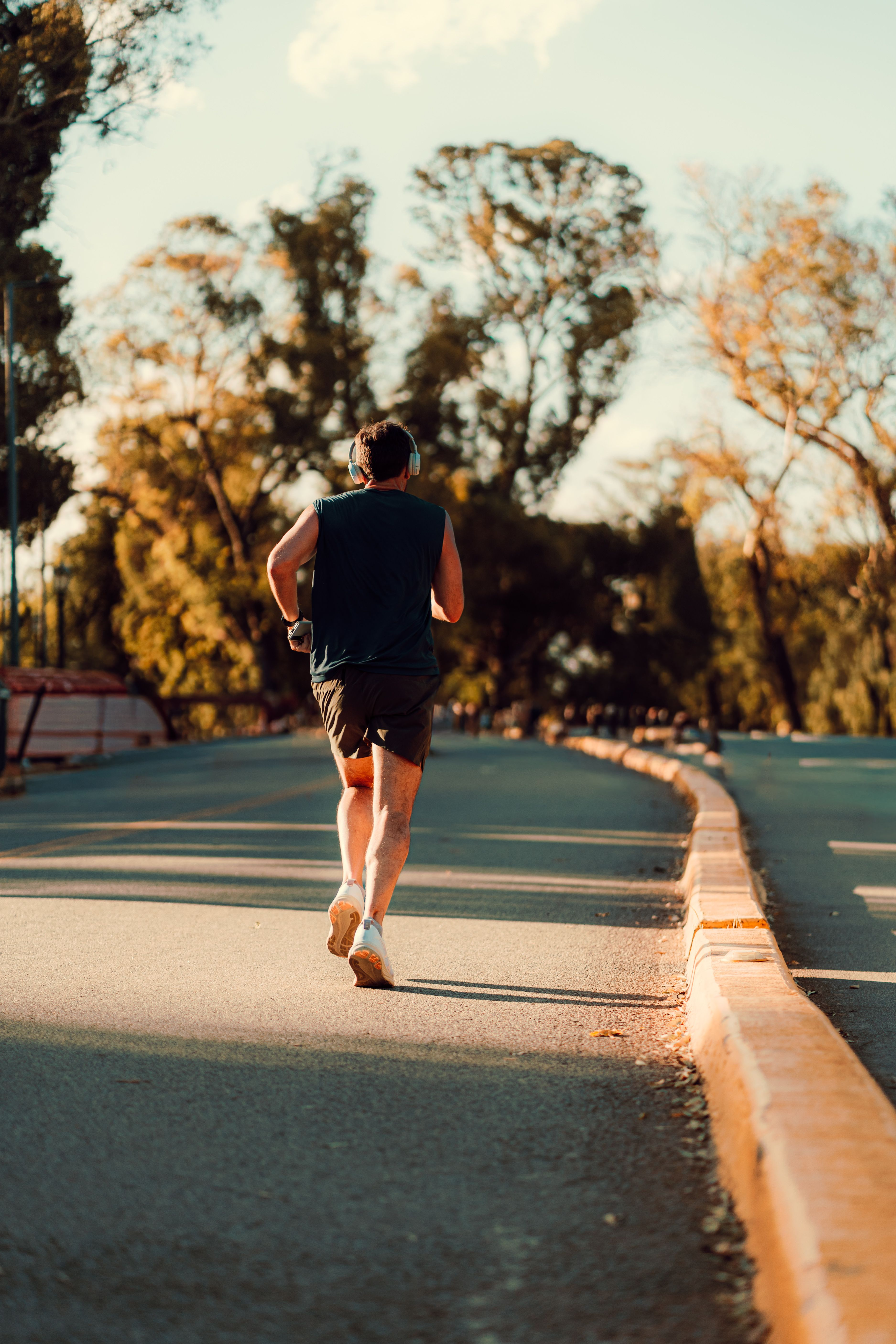 Runner from behind on a tree-lined path in autumn