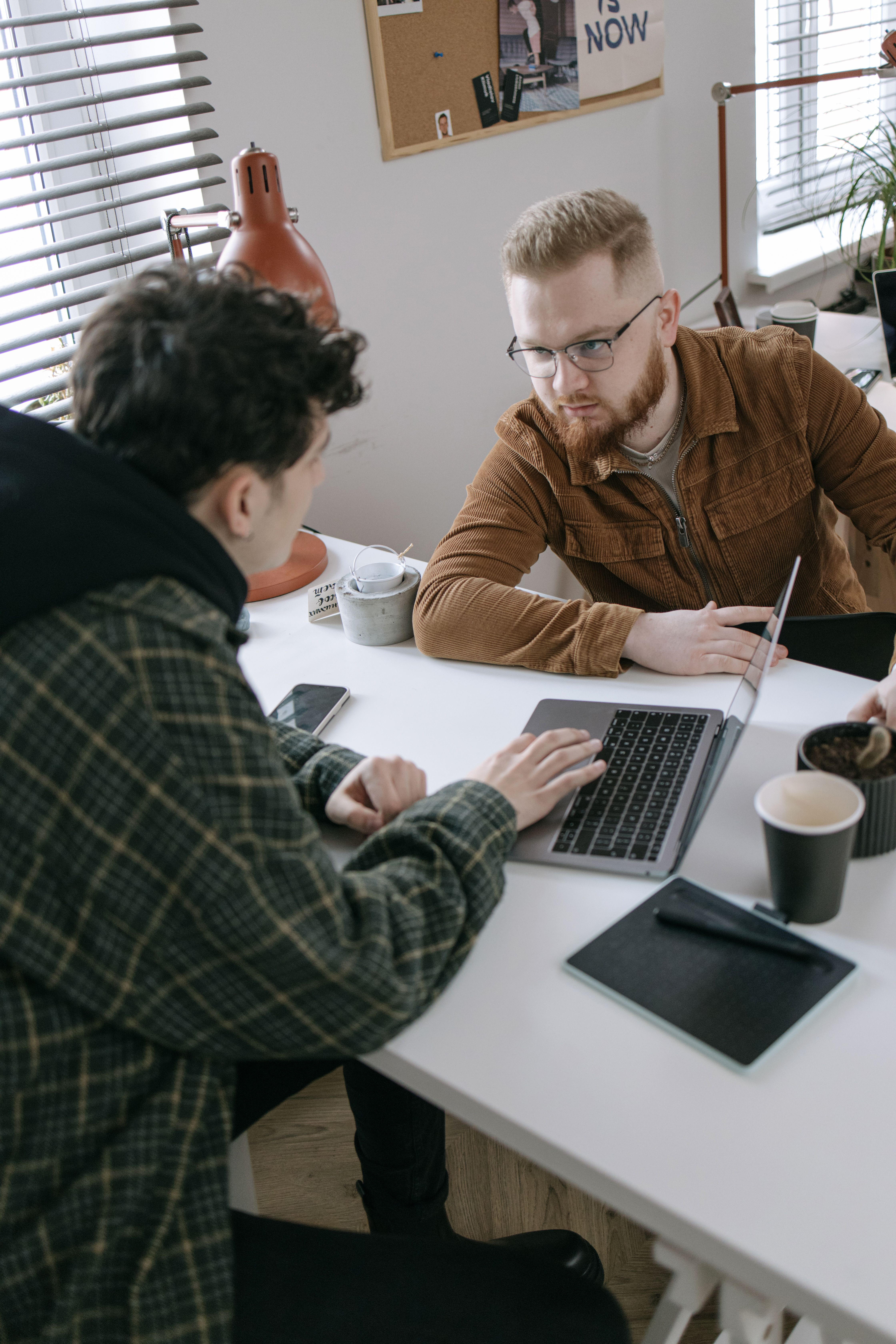 Two people in a meeting at a table with laptops