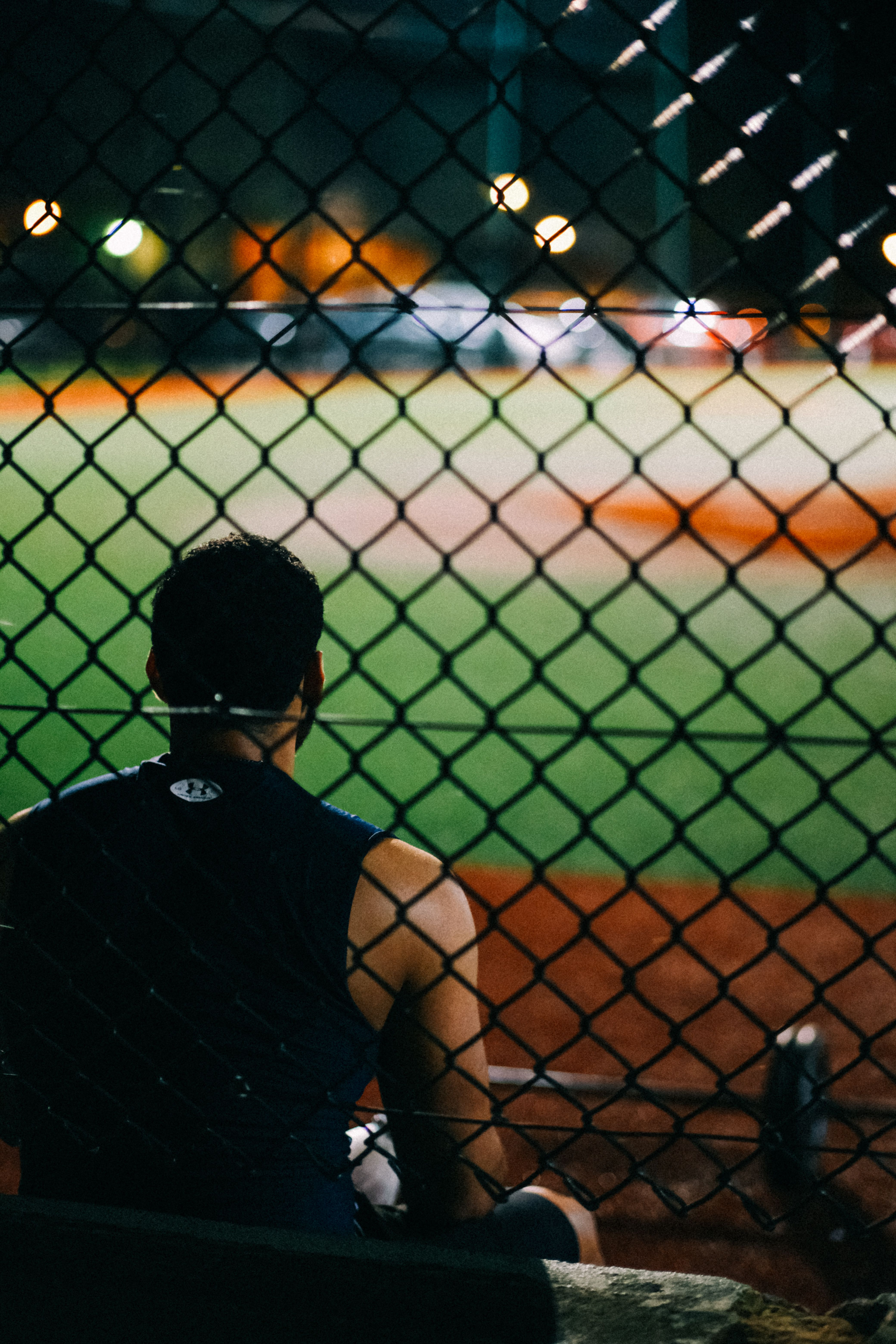 Athlete seated behind chain-link fence, stadium beyond