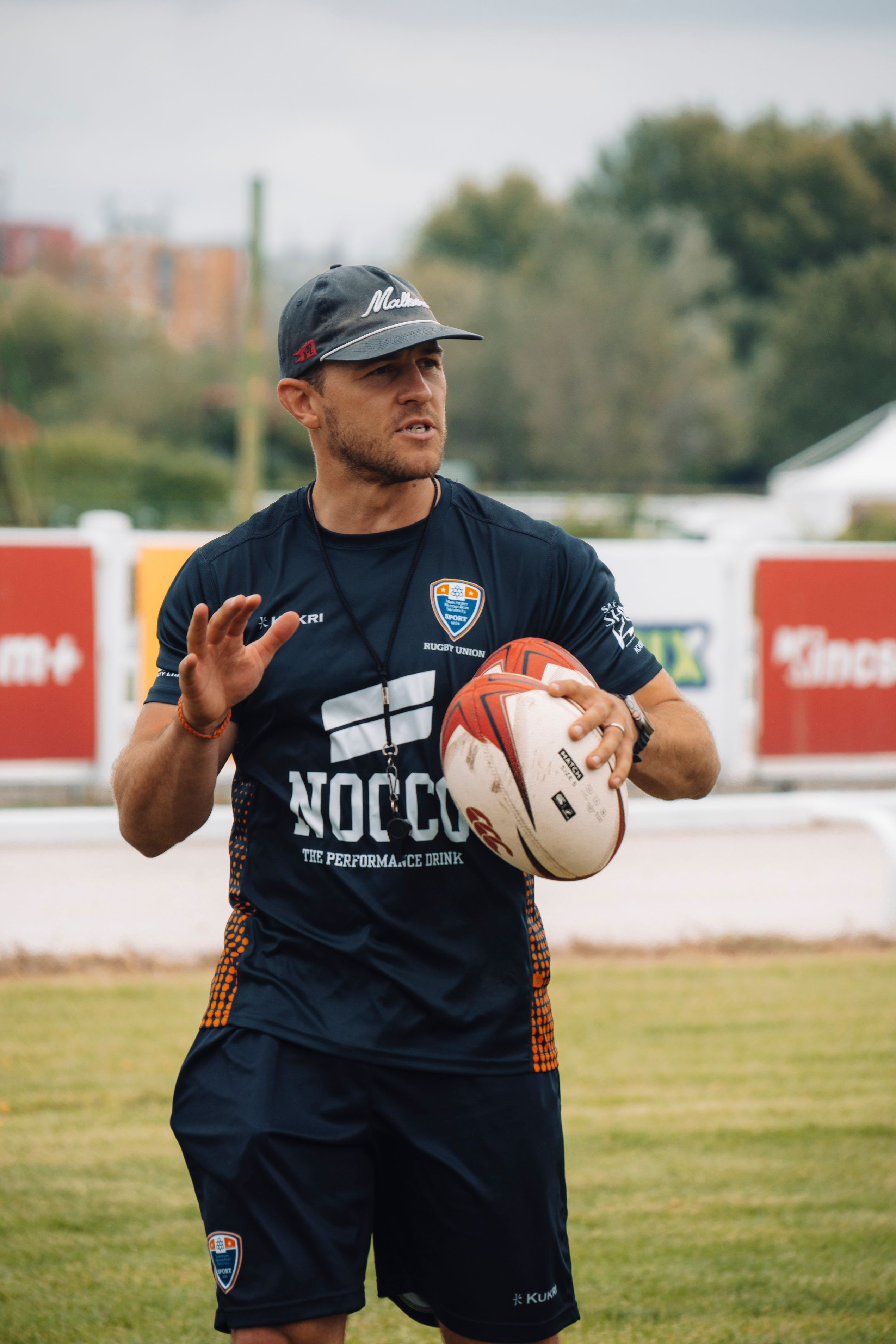 Hero — rugby coach holding a ball on the training pitch
