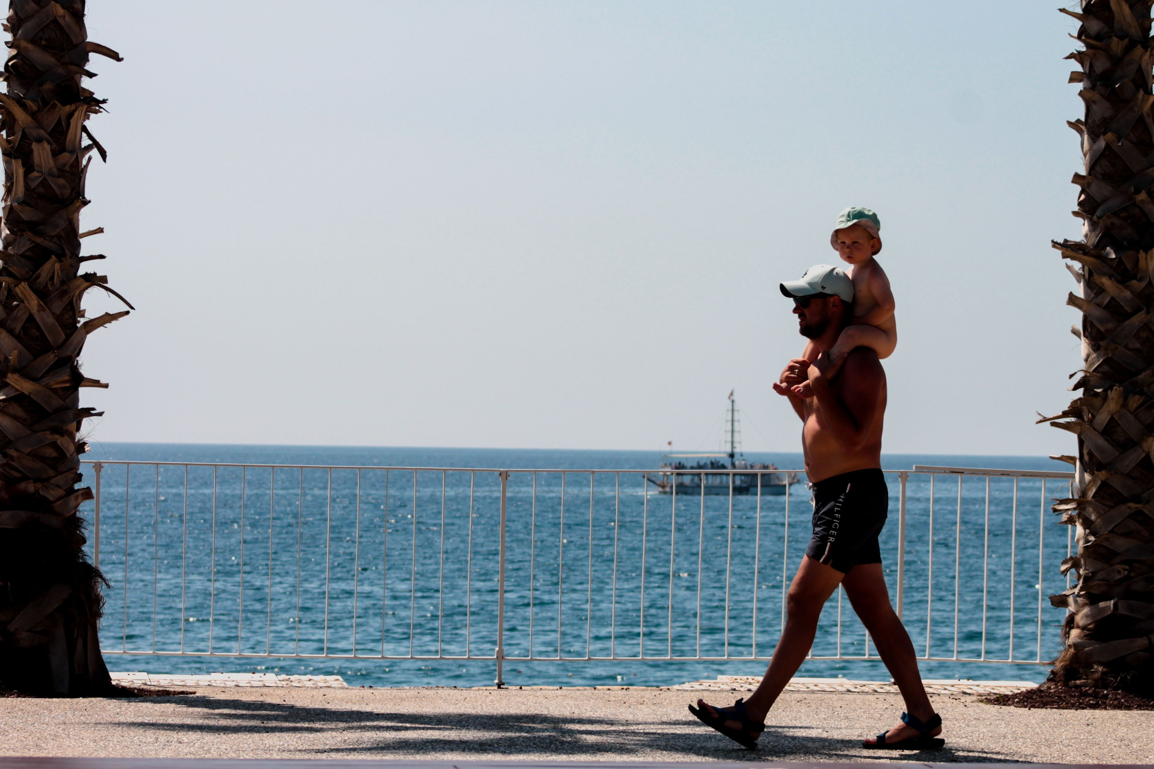 Parent carrying a child on their shoulders beside the sea