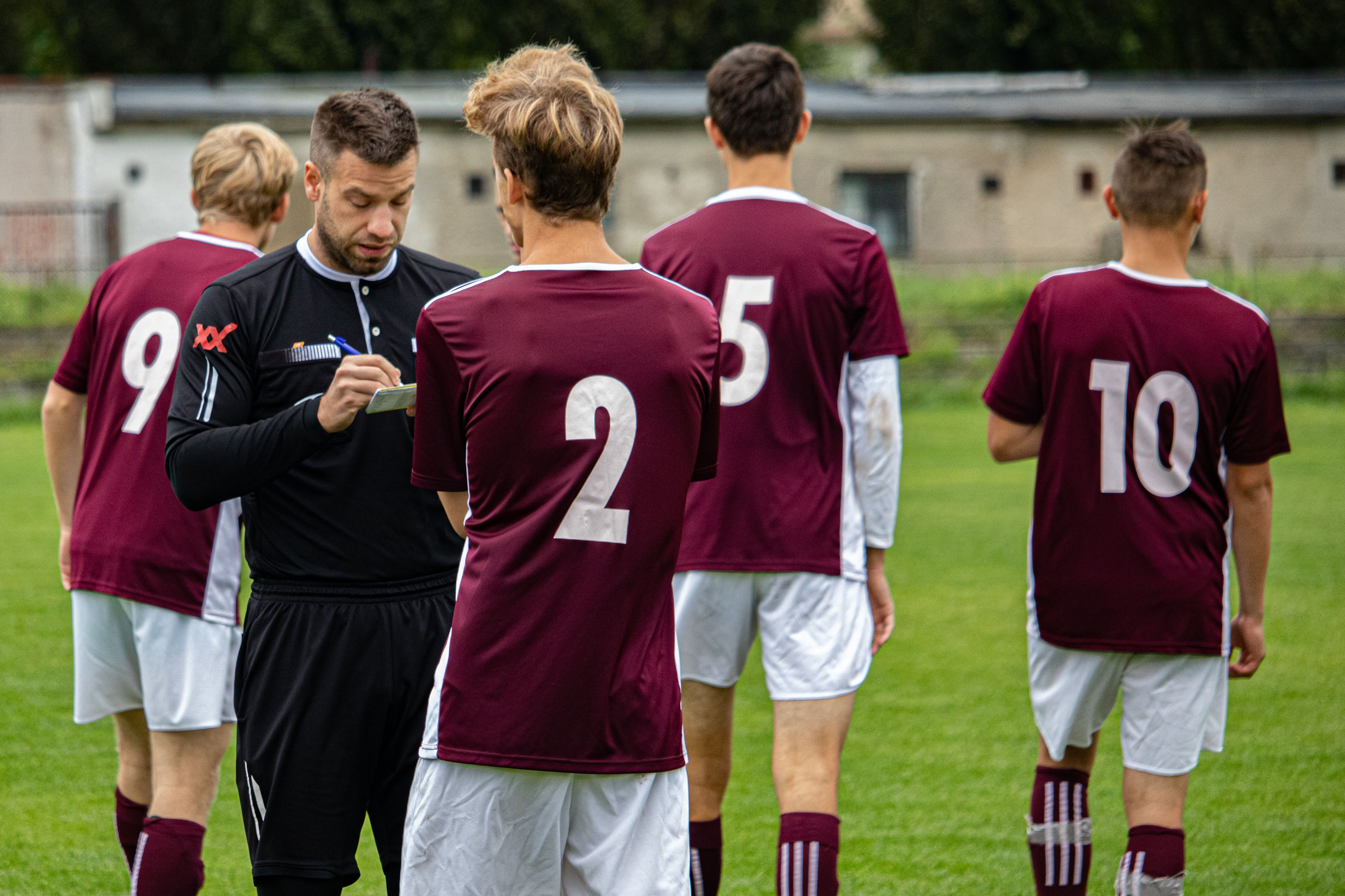 Coach with a youth team huddled together, seen from behind