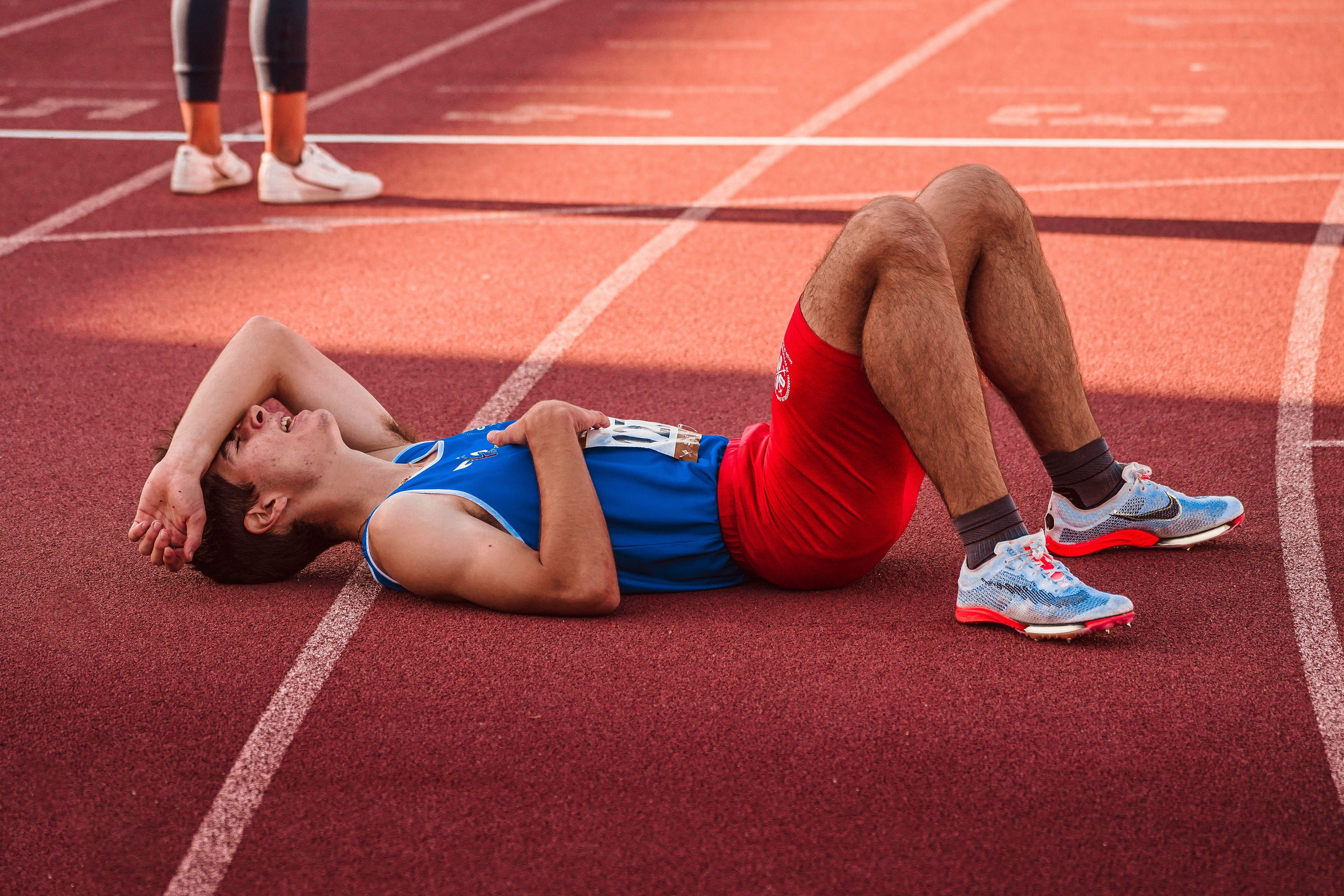 Two athletes lying on a running track after a race