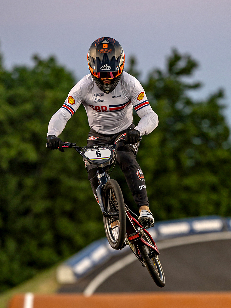 Portrait — BMX rider airborne over dirt jump