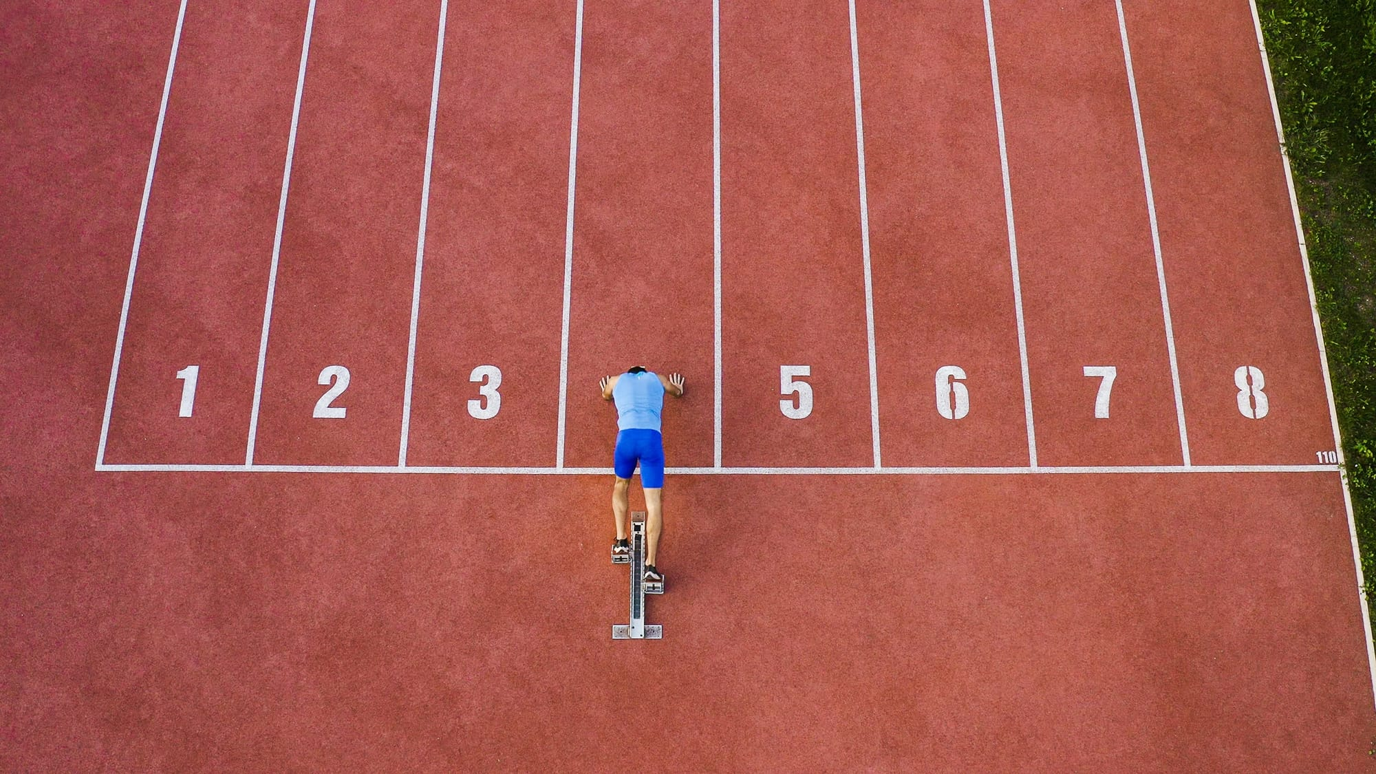 Runner in numbered lane on red track, overhead
