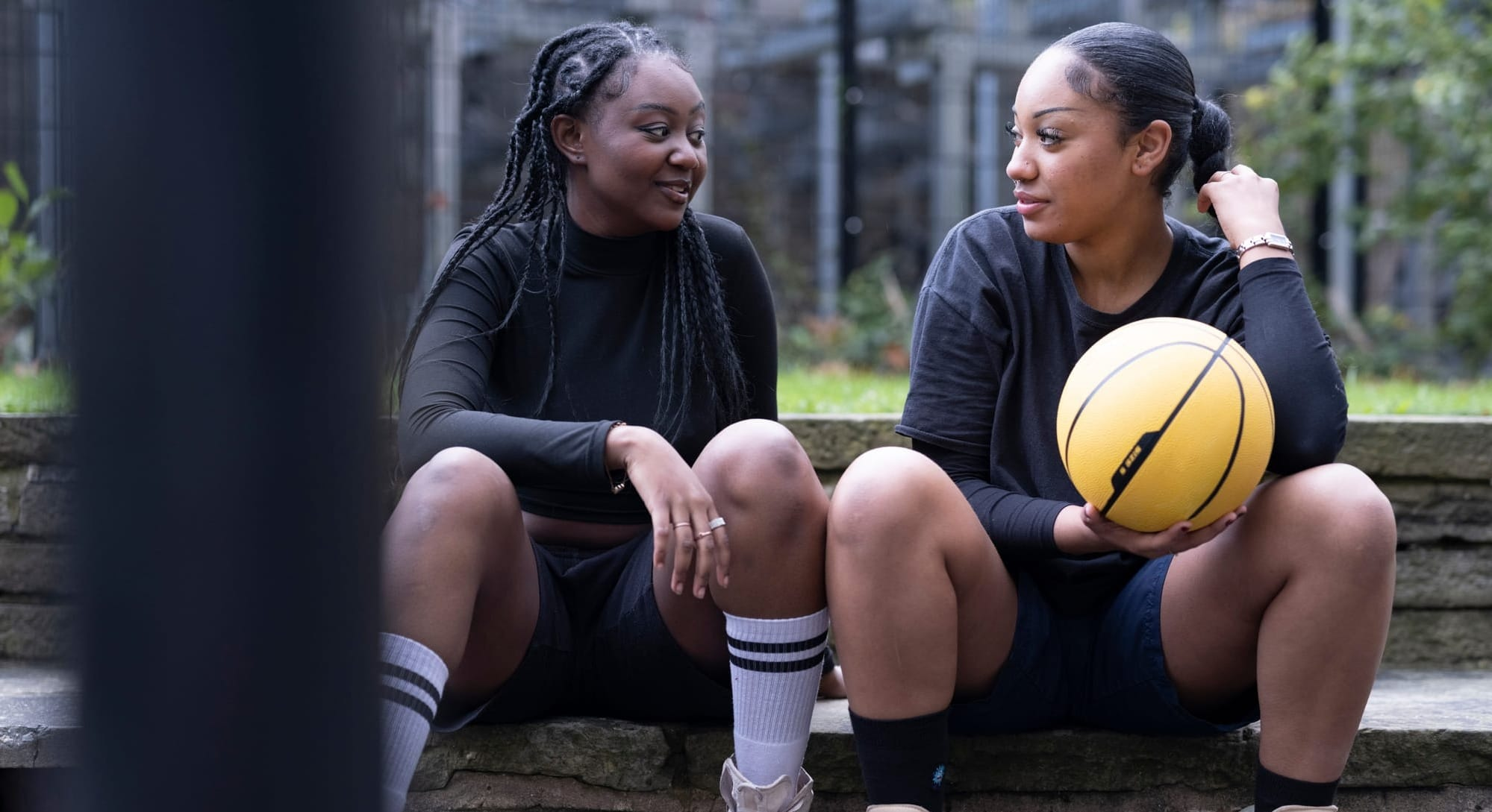 Two basketball players seated courtside talking
