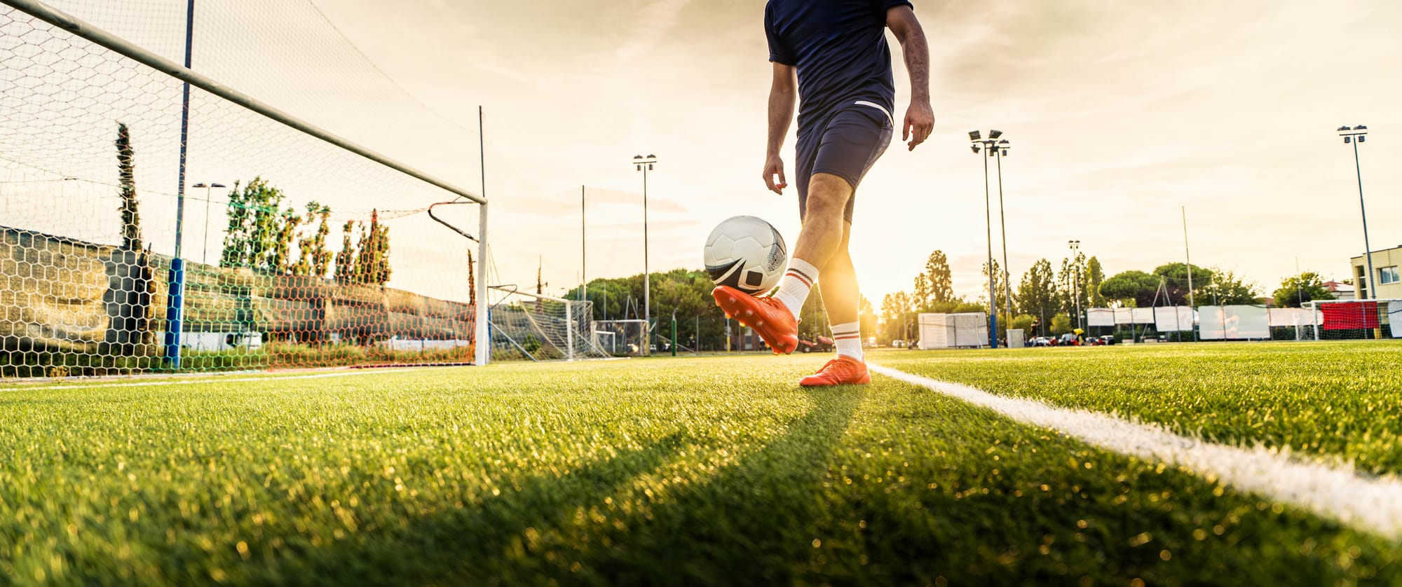 Footballer alone on floodlit pitch at dusk
