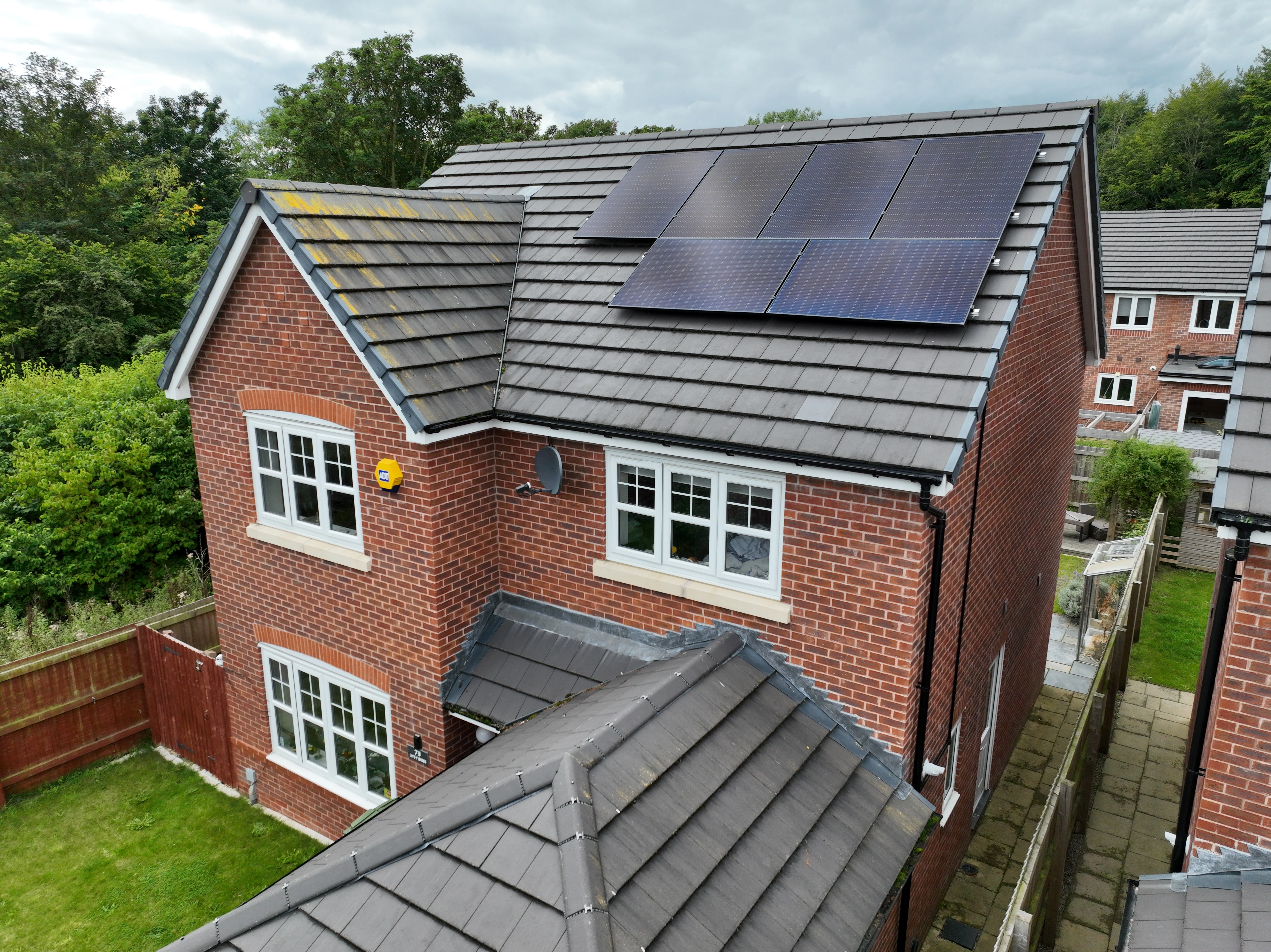Solar panels installed on a modern brick house roof generating renewable energy in a residential neighborhood