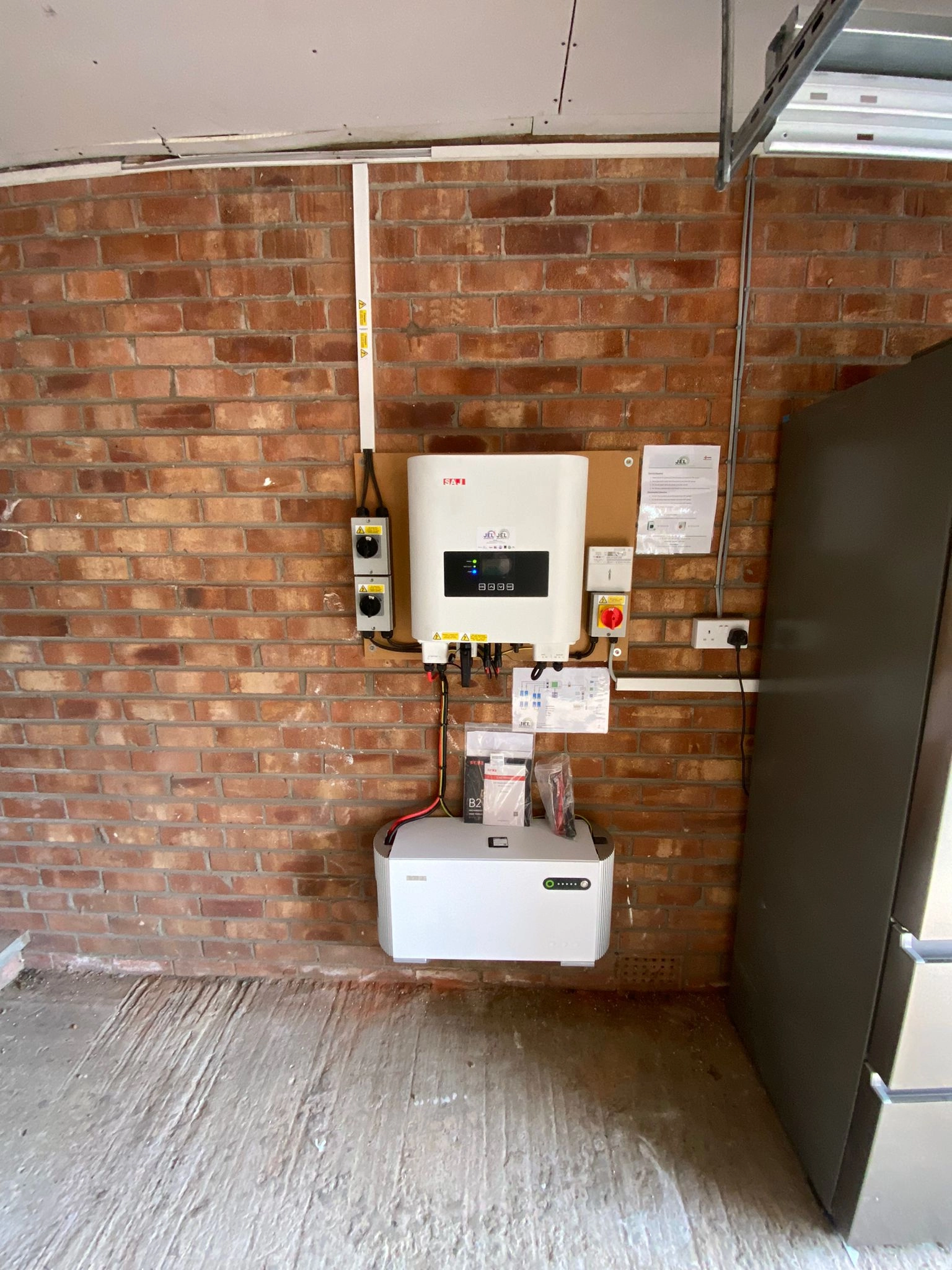 Home solar battery storage system and inverter installed on garage wall for renewable energy storage and management