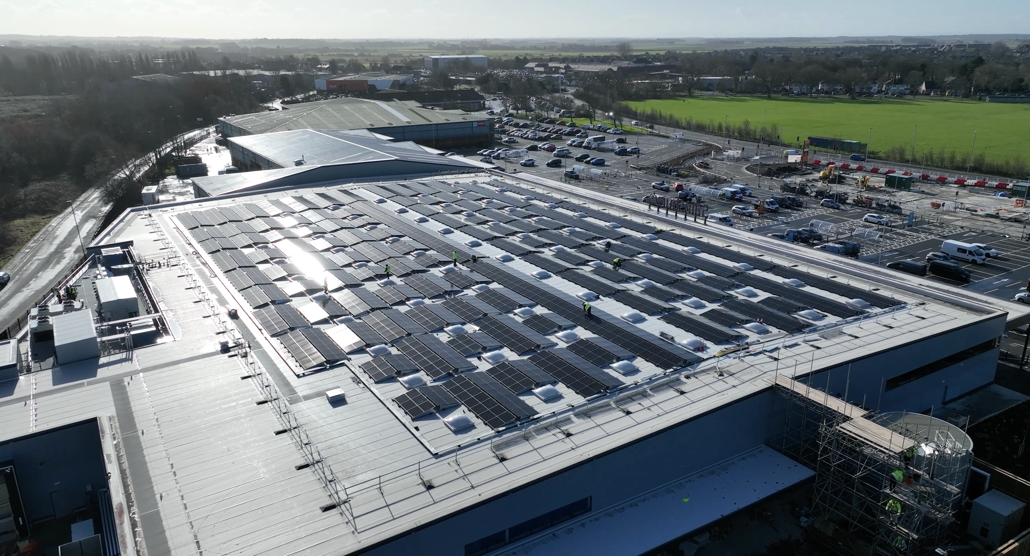 Aerial view of large commercial rooftop covered with solar panels generating renewable energy for industrial use