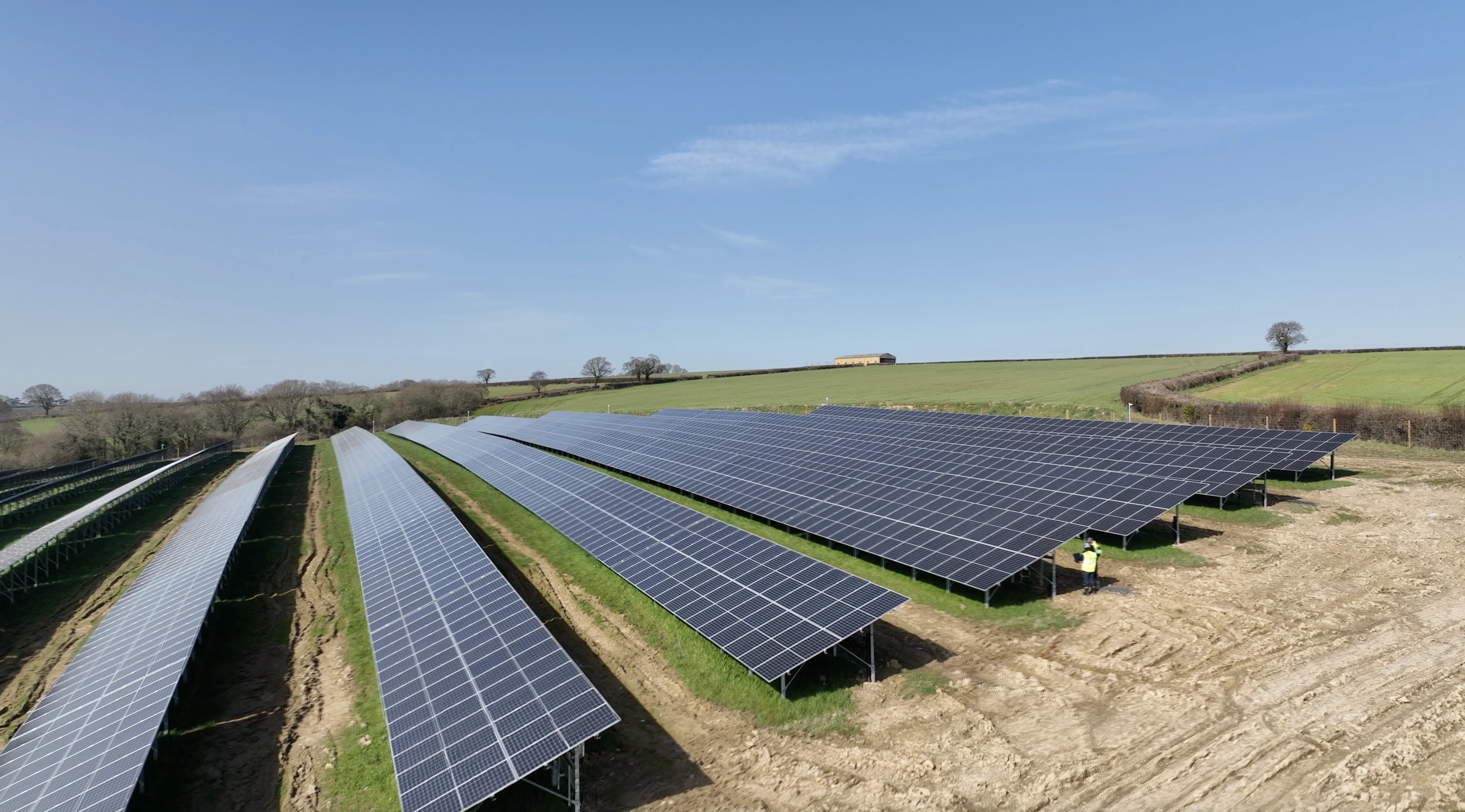 Large-scale solar farm with rows of photovoltaic panels generating renewable energy in a rural landscape