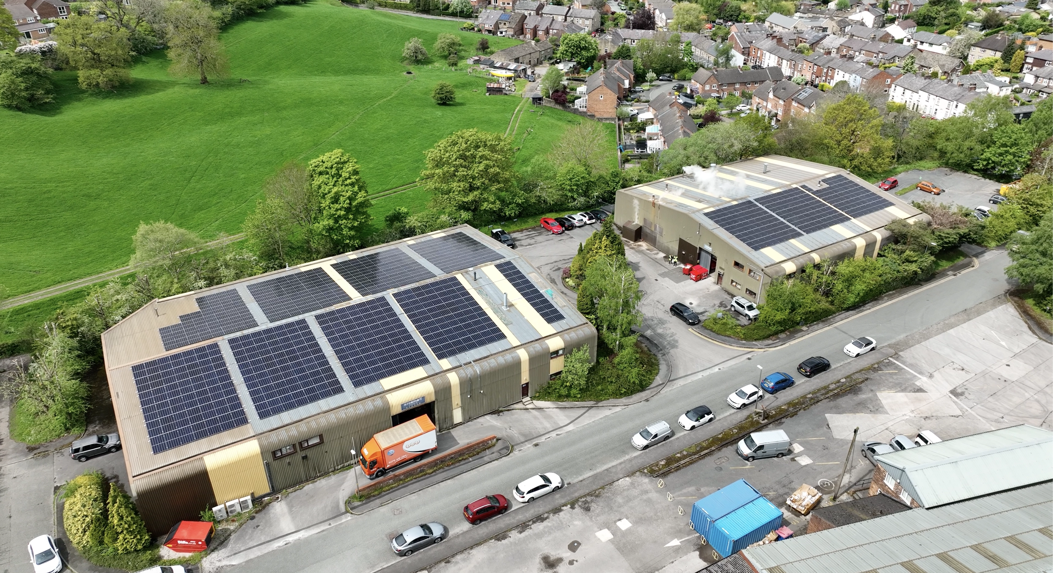 Aerial view of industrial buildings with rooftop solar panels generating renewable energy in a commercial area