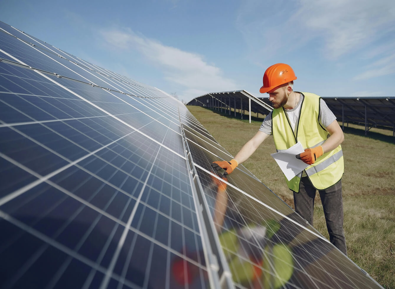 Technician inspecting solar panels at a solar farm, checking performance and maintenance with clipboard