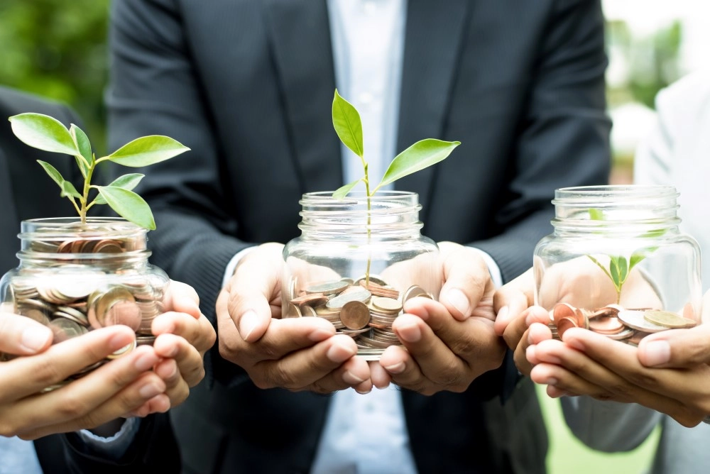 Hands holding jars filled with coins and small plants symbolizing growth, savings, and solar energy investment