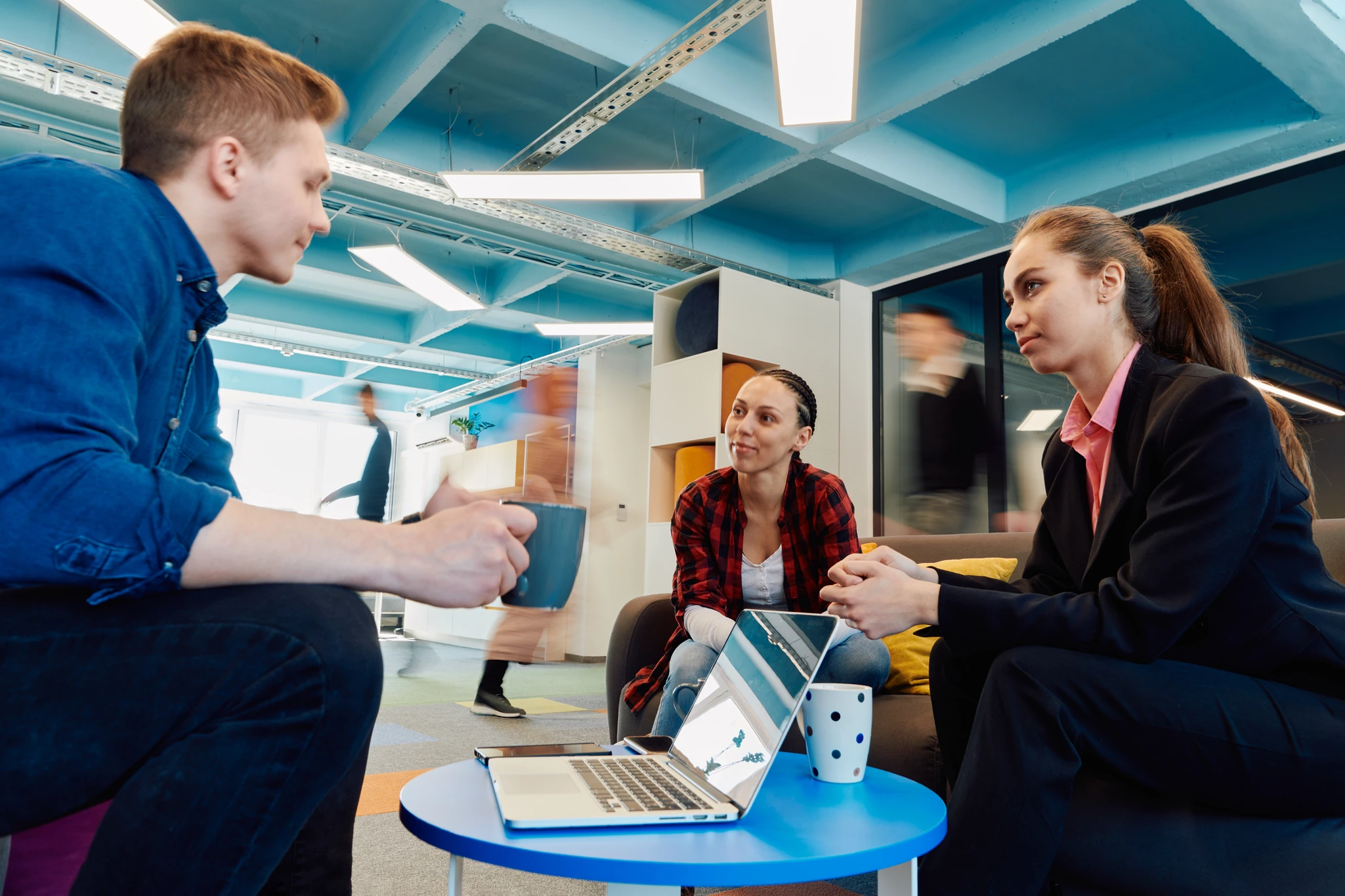 Colleagues talking over a laptop in a bright office breakout space