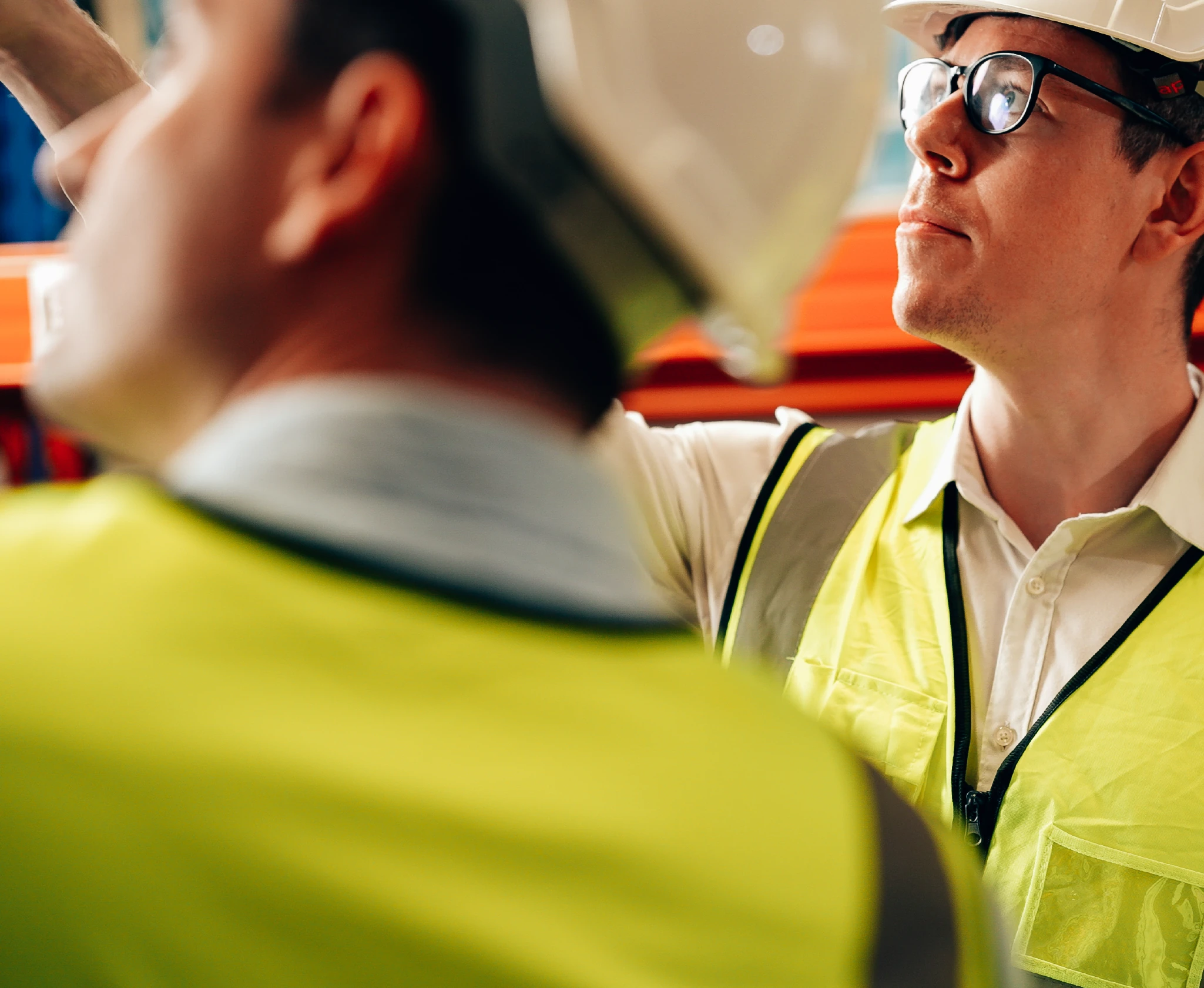 Two site workers in hard hats and hi-vis talking on site