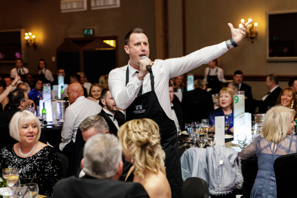 A waiter singing to the guests